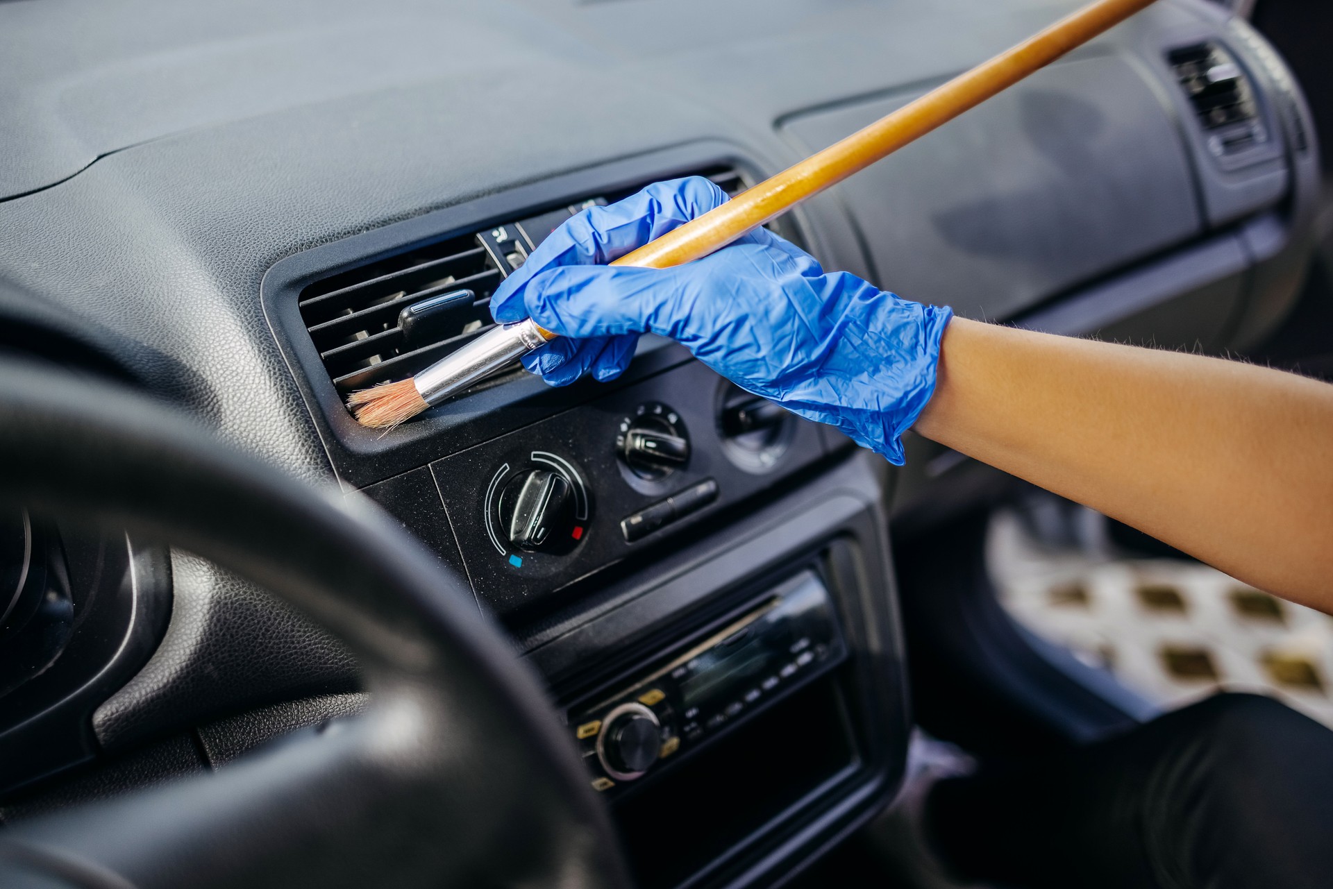 Young woman cleaning car interior using brush